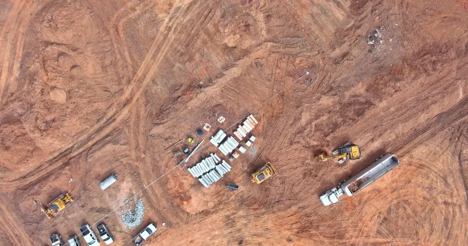 Aerial view of trucks and heavy machinery in a red earth landscape.